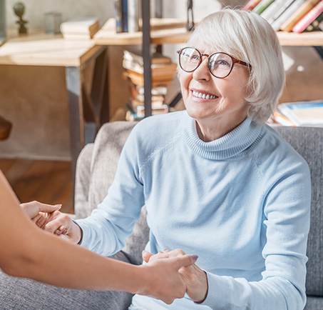 Cropped image of female professional caregiver taking care of elderly woman at home