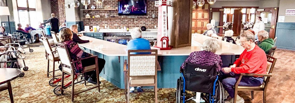 a group of senior citizens gathered around a pub at a local assisted living community