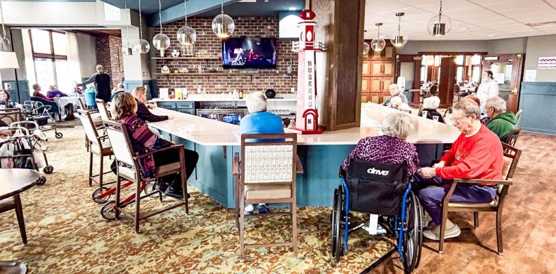 a group of senior citizens gathered around a pub at a local assisted living community